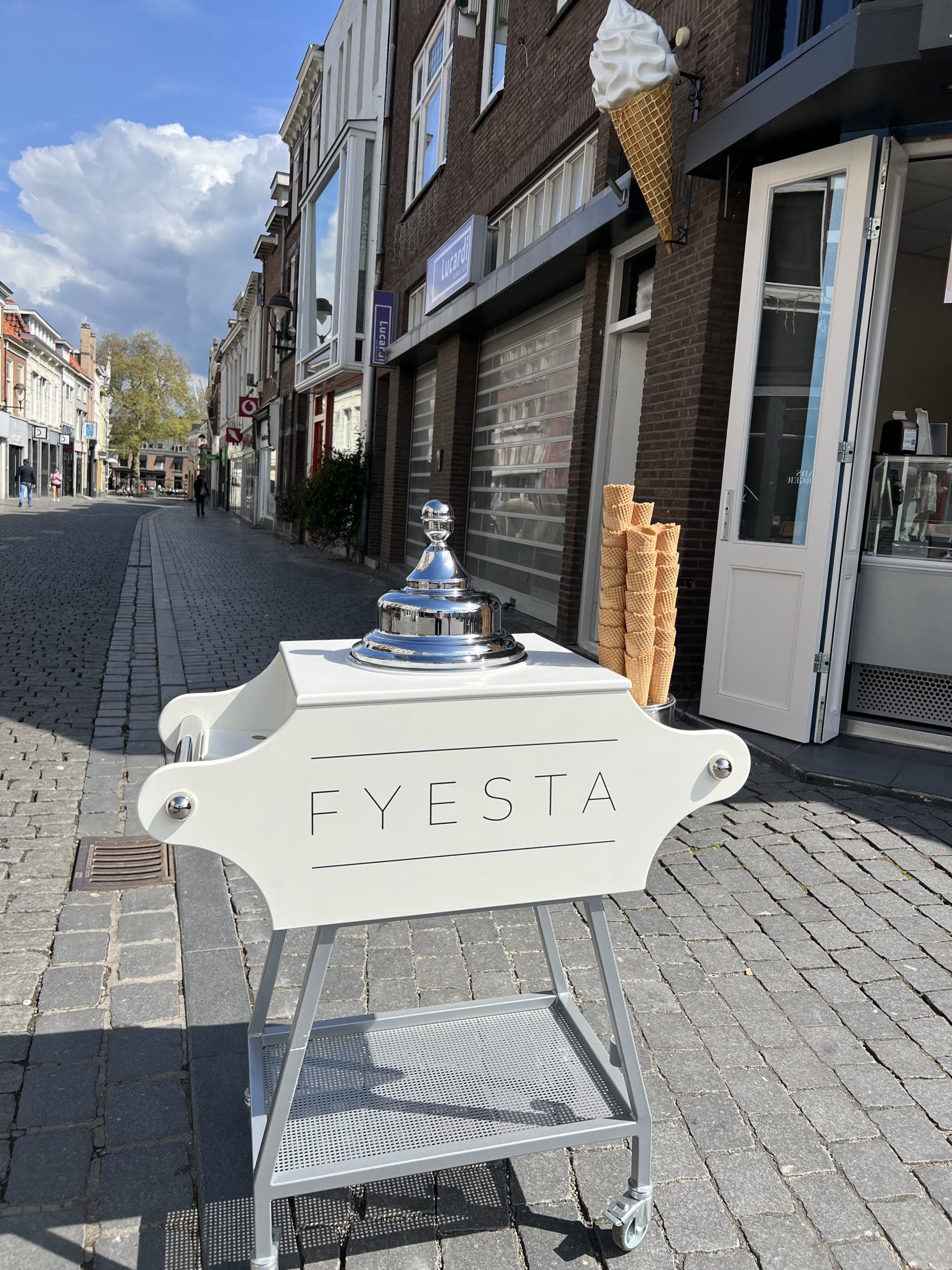 De kleine witte Fyesta Gelatobar op een geplaveide winkelstraat