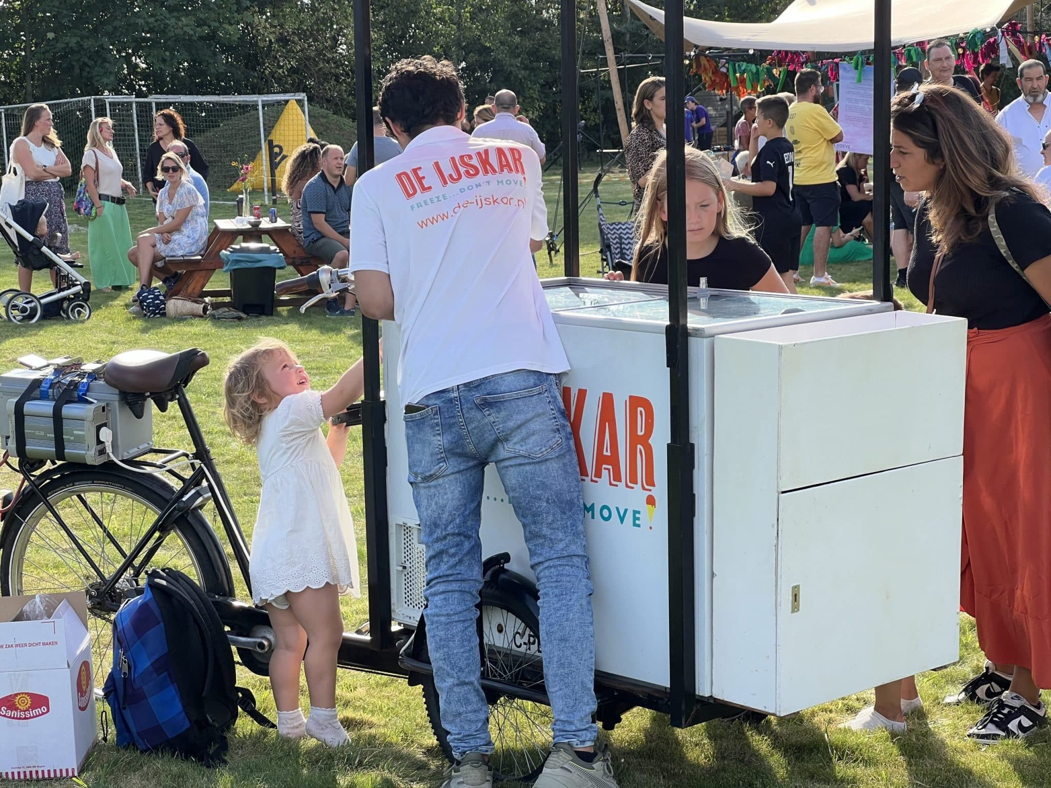 Kind kijkt toe hoe de ijscoman een bolletje schept bij de ijskar